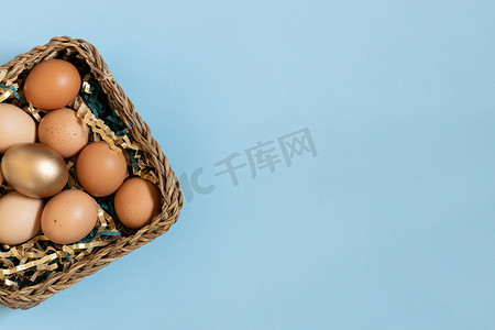 淡金色摄影照片_礼品篮，篮子里有复活节彩蛋、金色和天然彩蛋。