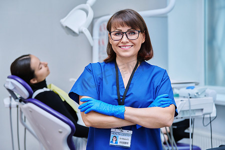 专业徽章摄影照片_女牙医与女病人坐在牙科椅上的画像