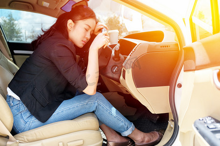 疲惫开车摄影照片_疲惫的年轻女人在她的车里睡着了