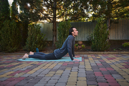 侧视一名运动员，一名运动员在户外练习体重训练时在健身垫上伸展身体