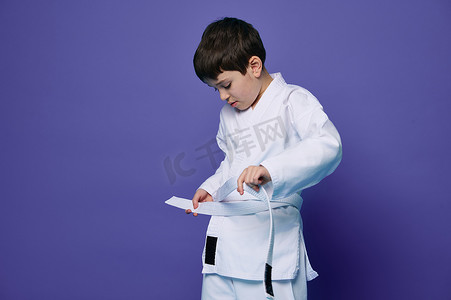 自信的欧洲少年穿上白色和服，腰系腰带，准备参加格斗运动。