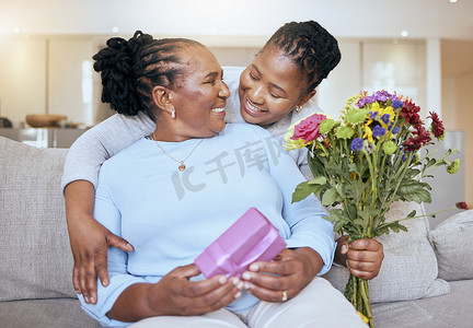 黑人妇女，母亲节，在沙发上用鲜花拥抱，为家里的妈妈送爱、盒子或礼物。