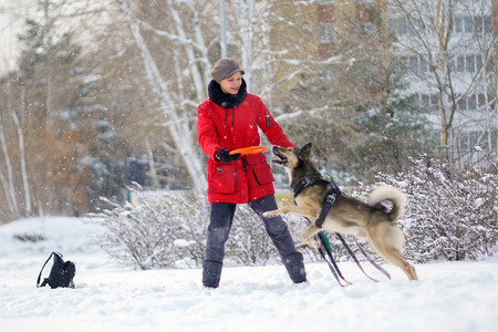 冬天的时候，女孩在雪地里和狗玩耍，空气中飘着雪花。