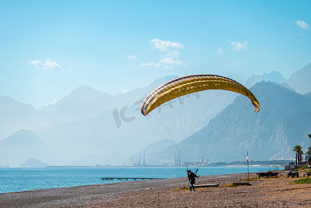 大风天在海边的沙滩上练习滑翔伞的男人