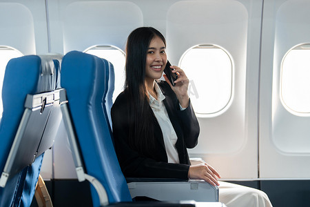 成功的年轻女商人坐在机舱里用手机说话