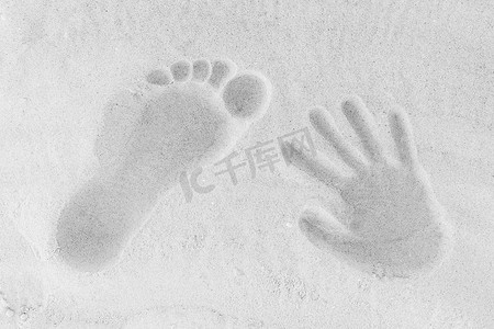 白色沙滩背景上一男一女的腿和手的痕迹特写