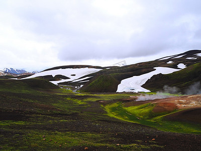 冒热气摄影照片_冰岛 Landmanalaugar 山冒着热气的地热河溪流，有郁郁葱葱的绿色苔藓和雪​​洞