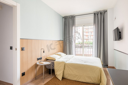 阳台人摄影照片_卧室配有可容纳两人的大床，以玻璃推拉门为背景，可通往小阳台。
