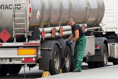 白俄罗斯，戈梅利地区 — 2020 年 8 月 21 日：一名身着工作服的卡车司机抓住接地线或电线将机器接地。