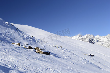 雪中小屋摄影照片_风景秀丽的冬季背景中的旧牧场小屋