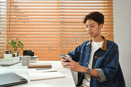 坐在家庭办公室时使用移动应用、浏览社交媒体的轻松帅哥