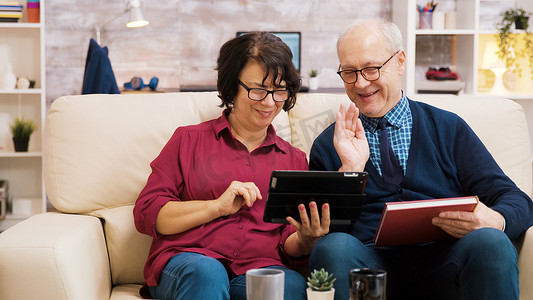 老年夫妇在视频通话中向平板电脑挥手