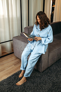 一位穿着蓝色西装的年轻女子坐在沙发靠背上，手里拿着一台平板电脑。