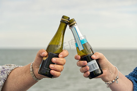 游轮上的女孩在出海旅行时碰杯小瓶香槟。