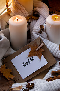 THANKFUL 文本贺卡概念 在窗台上舒适的家中庆祝感恩节秋季假期 Hygge 审美氛围 秋叶香料和蜡烛在温暖的黄色灯光下的针织白色毛衣上。
