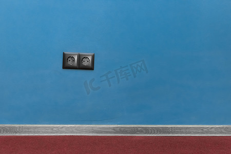 蓝墙背景及踢脚板地板踢脚线地板材料上的双黑插座电源家庭能源供电