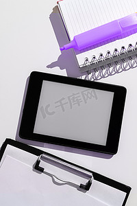 桌上贴纸摄影照片_平板电脑屏幕上有重要的想法，并在带有笔记本和记号笔的办公桌上贴着笔记。