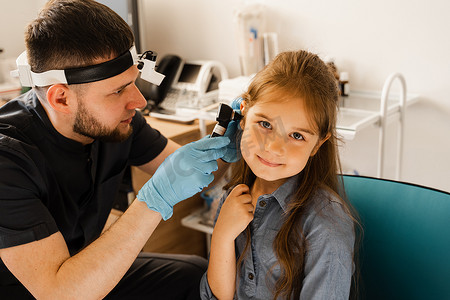 耳鼻喉科医生耳鼻喉科医生通过耳镜观察一个小女孩的耳朵。