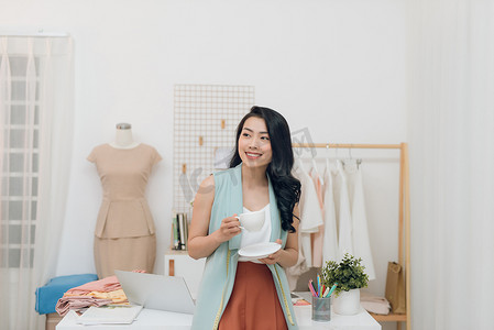 快乐的亚洲时装设计师女商人在工作室的画像。