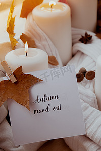 文本贺卡概念上的秋天心情在窗台上舒适的家中庆祝秋季假期 Hygge 审美氛围秋叶、香料和蜡烛在温暖的黄色灯光下针织白色毛衣。