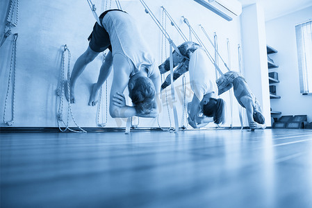人们挂在绳子上练习瑜伽在健身房伸展。
