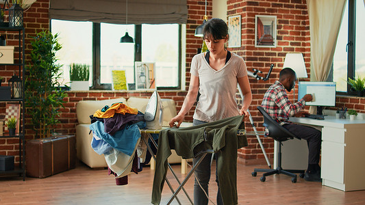 女性洗完衣服后在公寓里熨衬衫