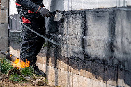 在房屋建造过程中用覆盖的沥青带对墙壁进行防水处理