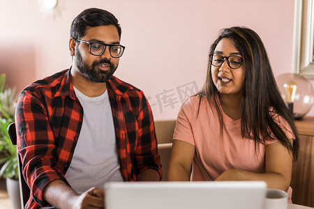 拉丁裔或印度男女夫妇在客厅里使用笔记本电脑进行视频通话。