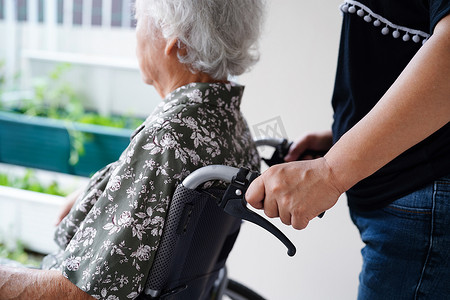护理人员帮助亚洲老年妇女残疾患者坐在医院的轮椅上，医疗理念。