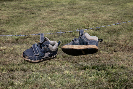 一双儿童跑鞋挂在带刺的铁丝网上