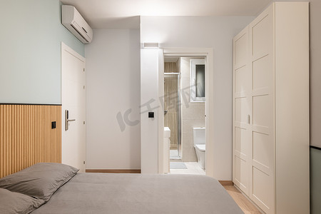 双人床配有灰色床单、内置衣柜和空调，可俯瞰紧凑型淋浴间。