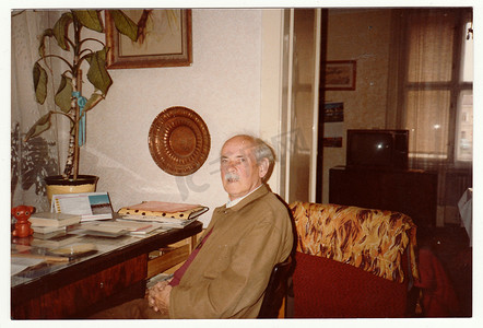 复古照片显示男人坐在椅子上，大约 1980 年代。
