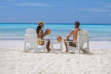 普拉兰塞舌尔热带岛屿海滩上的男女情侣喝着椰子饮料