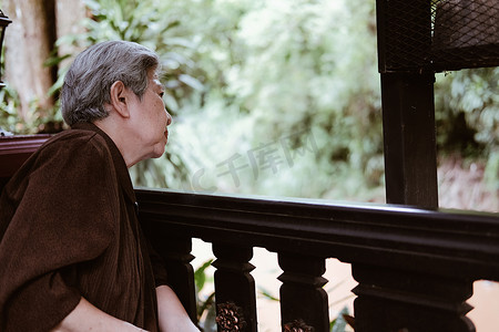 亚洲老年妇女在阳台露台上休息放松。