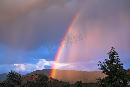 阳光彩虹摄影照片_阳光冲破风雨如磐的天空，形成一道奇妙的彩虹