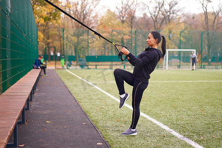 trx摄影照片_在运动场上使用 trx 进行女运动员训练。