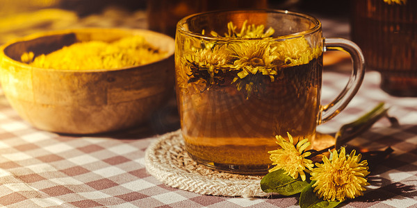 蒲公英茶摄影照片_桌上玻璃杯中的蒲公英花健康茶。