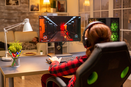 功能强大摄影照片_深夜在客厅玩功能强大的电脑 PC 的女性游戏玩家的后视图