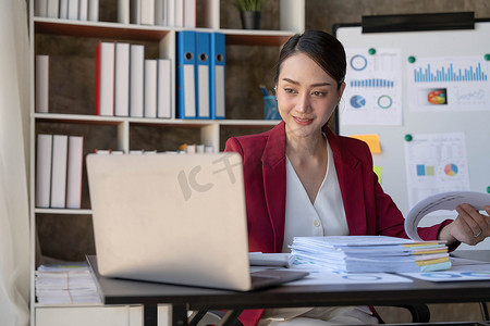 亚洲女商人使用笔记本电脑，在办公室工作，在办公桌上使用计算器文档，进行规划分析财务报告、商业计划投资、财务分析概念。