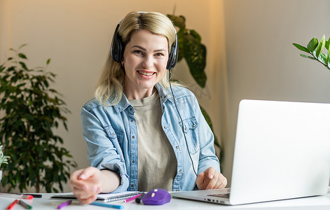 漂亮的女学生带着可爱的微笑在上网本上敲键盘，在大学讲课后放松，漂亮快乐的女人在笔记本电脑上工作