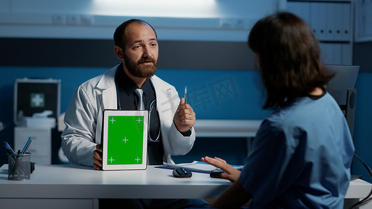 全科医生向护士解释病人的疾病症状，护士指着带绿屏的平板电脑
