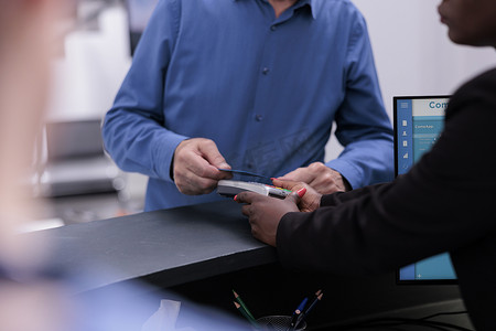 老年患者站在登记柜台用信用卡支付药物治疗和检查费用