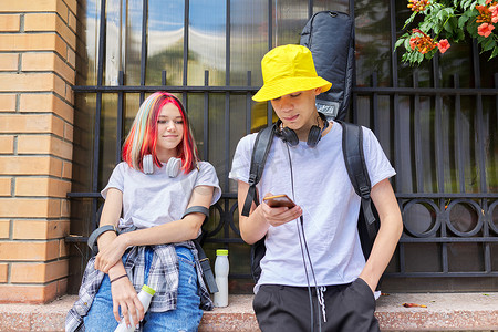 城市街道上几个拿着智能手机的热门青少年朋友