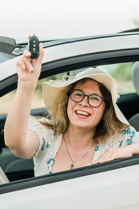 汽车司机女人微笑着展示新车钥匙和汽车。