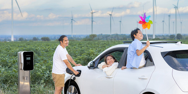 技术进步摄影照片_电动汽车风电场进步幸福家庭的概念。