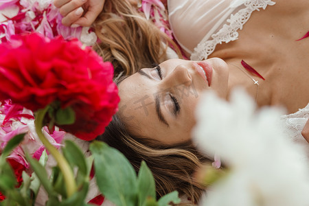 家里一个穿着白色睡衣的漂亮女孩，在一张大床上被春天的花朵包围着。