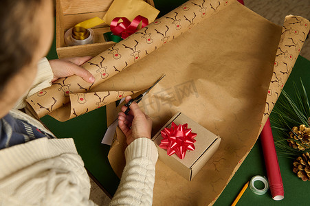 新年信封摄影照片_从头顶看一位女士正在切割包装纸以包装圣诞节、新年或其他庆祝活动的礼物