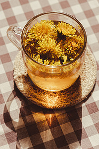 桌上玻璃杯中的蒲公英花健康茶。