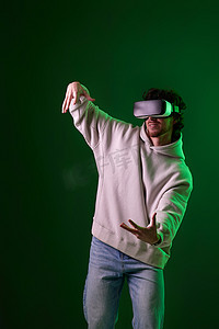 vr虚拟现实摄影照片_戴着 vr 眼镜和运动衫的男人在蓝色背景上玩耍。