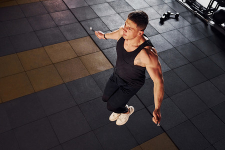 穿着运动服的强壮男子用跳绳在健身房锻炼一天